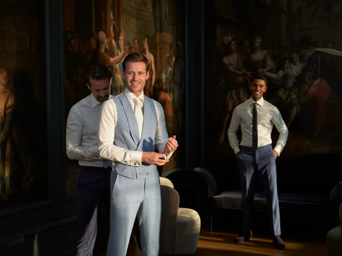 Groom in a light blue vest getting ready with groomsmen