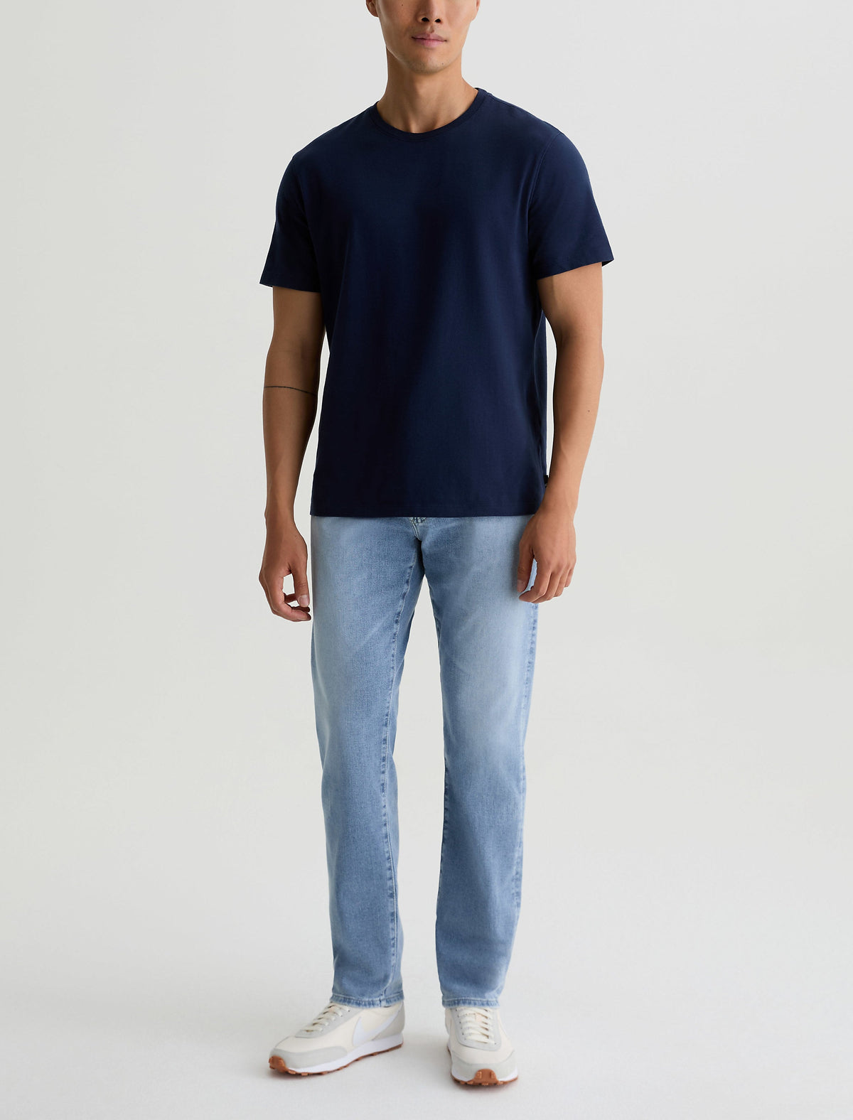 Man wearing the AG Everett jean in a light indigo wash with a navy tee