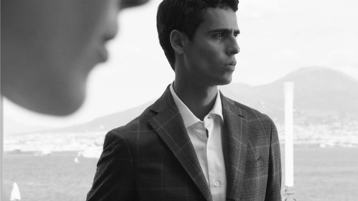 Man in a grey check Barba Napoli jacket and white shirt overlooking the Bay of Naples.