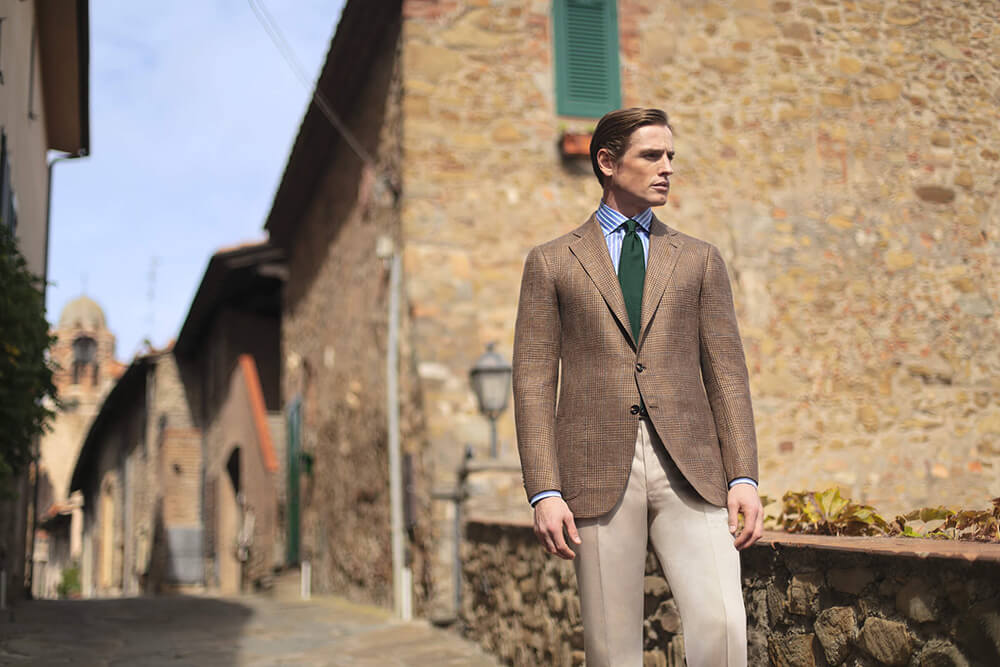 Man in Cesare Attolini brown jacket on a village street