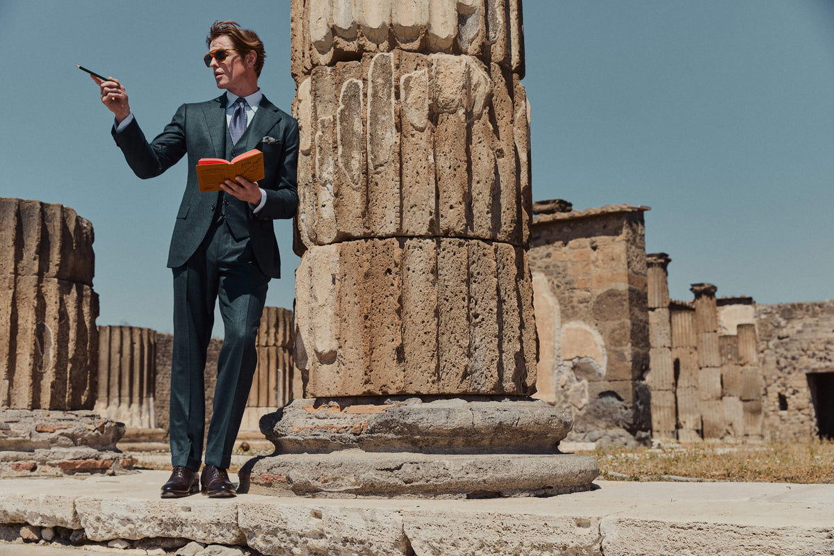 Man in a suit leaning on a pillar