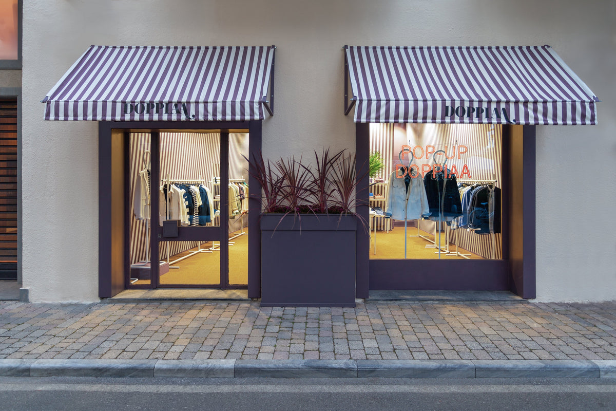 Doppiaa boutique storefront with striped awnings