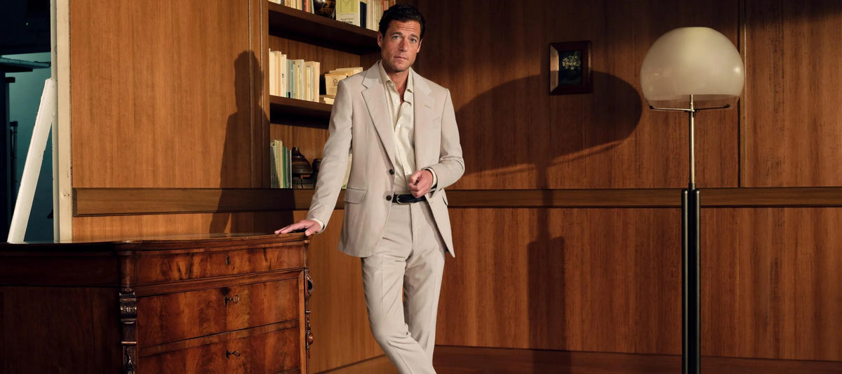 Man in beige suit in a wood-paneled study
