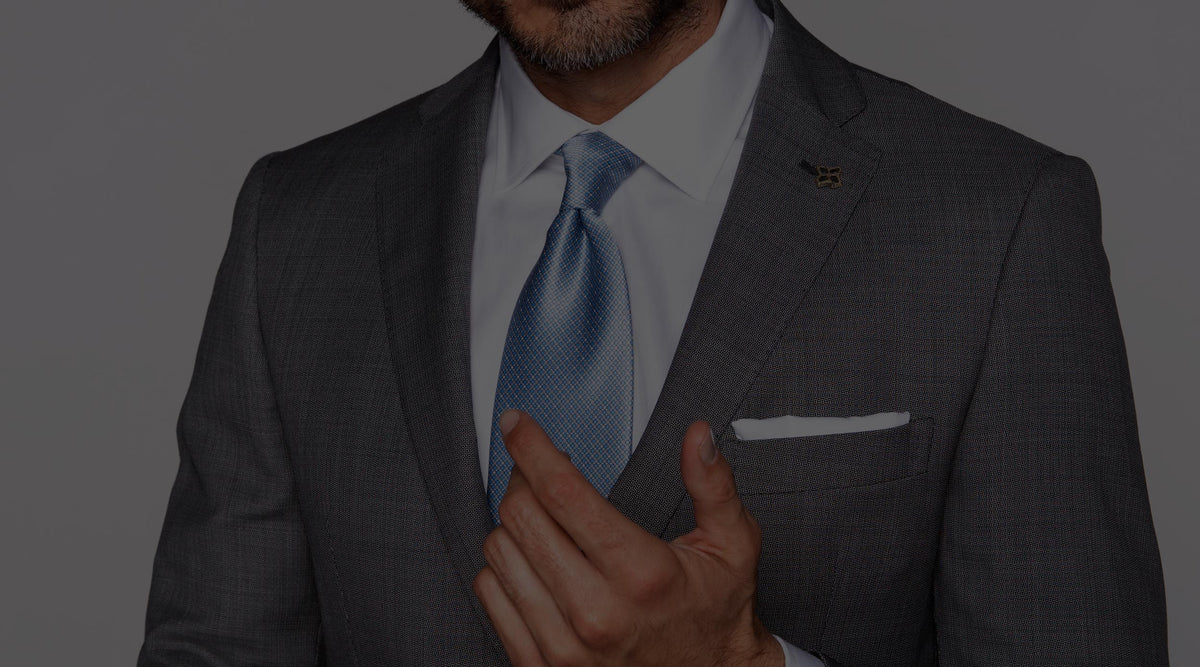 Man in charcoal suit adjusting an Italo Ferretti blue silk tie