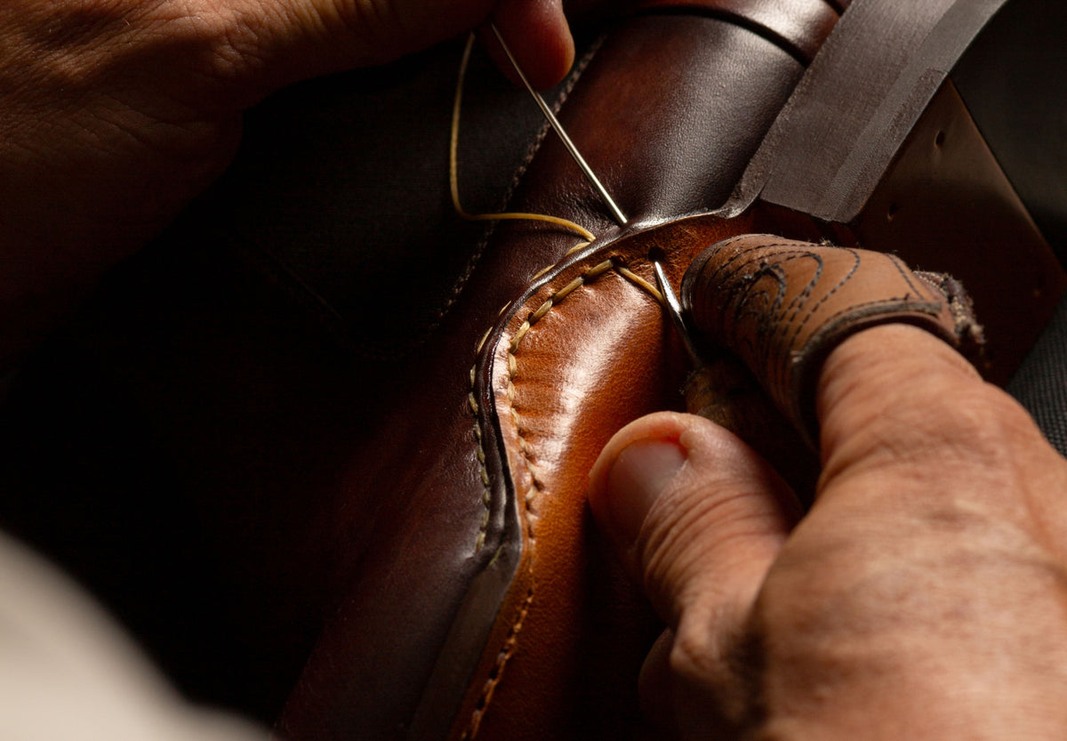 Artisan hand-stitching a Magnanni brown leather shoe
