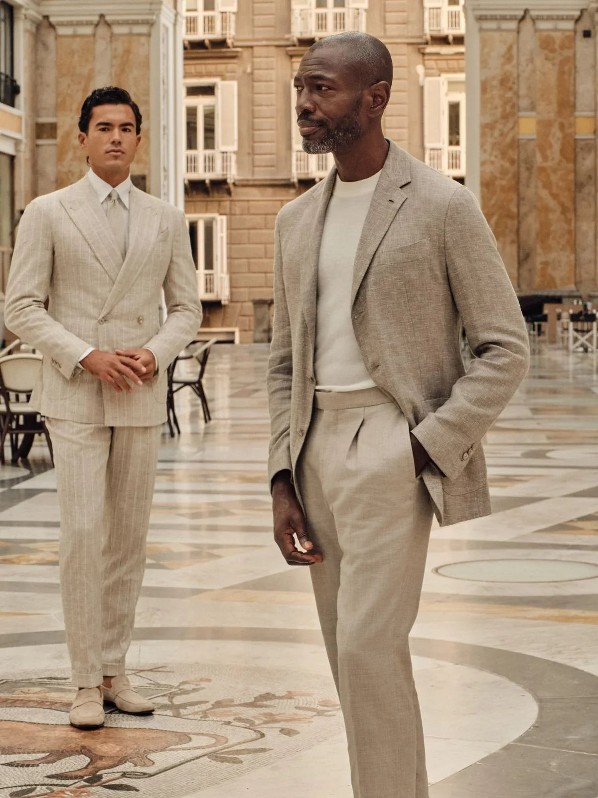 Two men in beige suits in a grand arcade