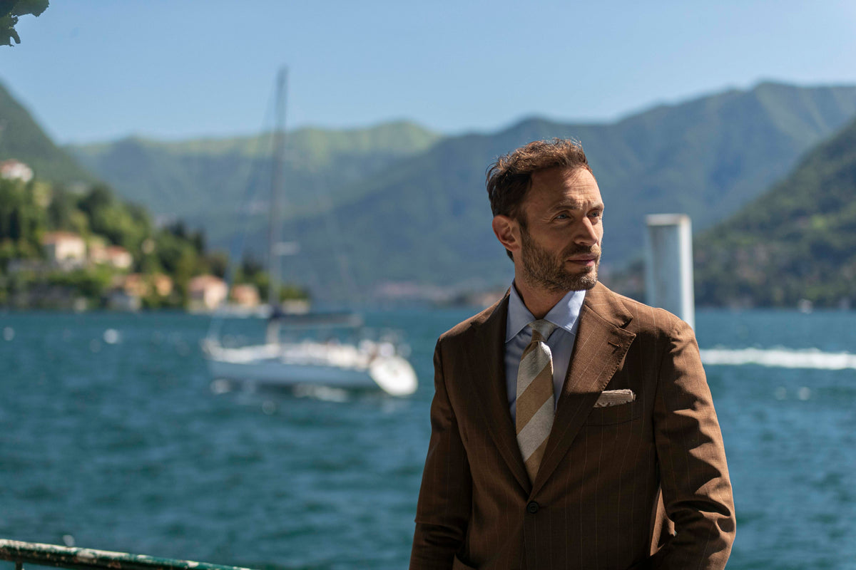 Man in Paolo Albizzati brown jacket and tie by a lake