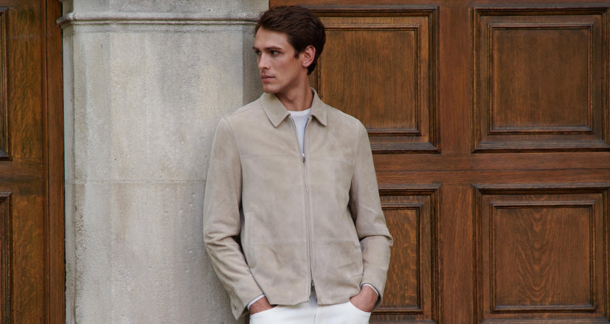 Man in Patrick Assaraf beige suede jacket by a wooden door