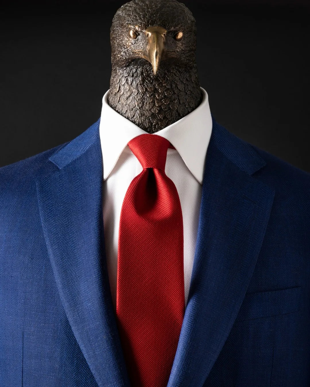Stefano Ricci eagle emblem dressed in a navy suit, white shirt and red silk tie.
