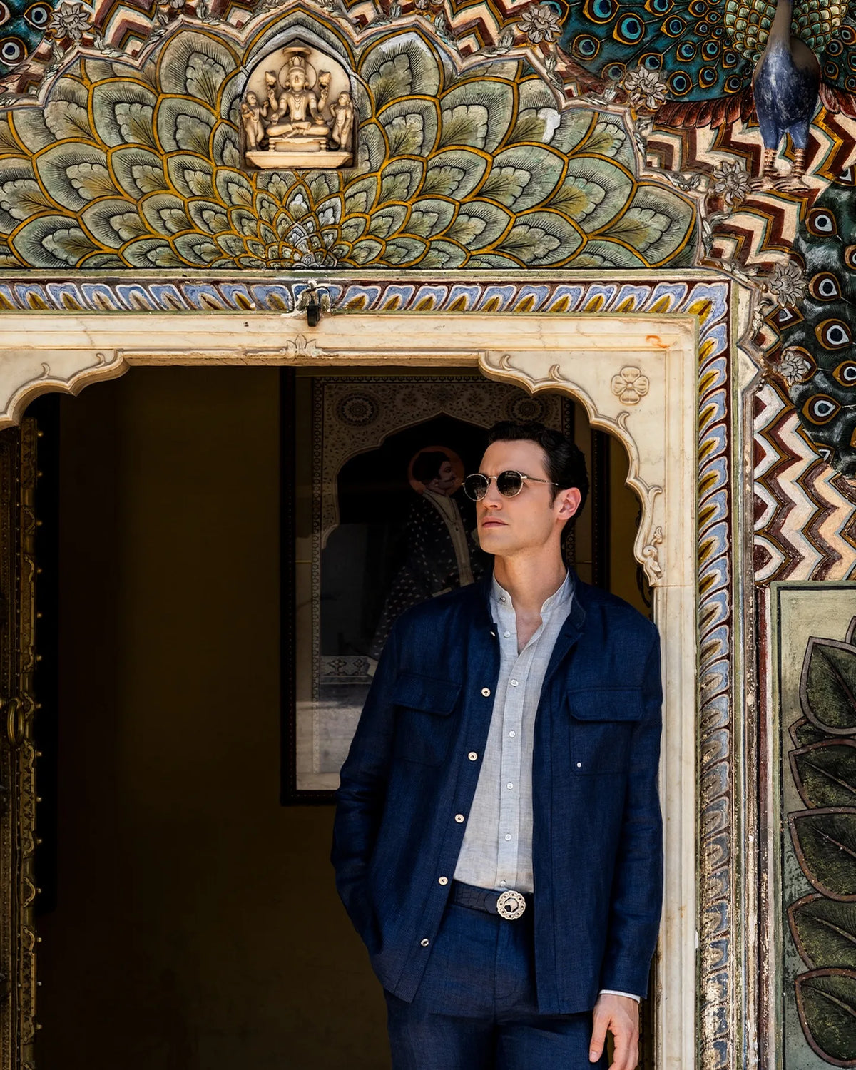Man in a navy Stefano Ricci denim jacket and light blue shirt in a palace doorway.