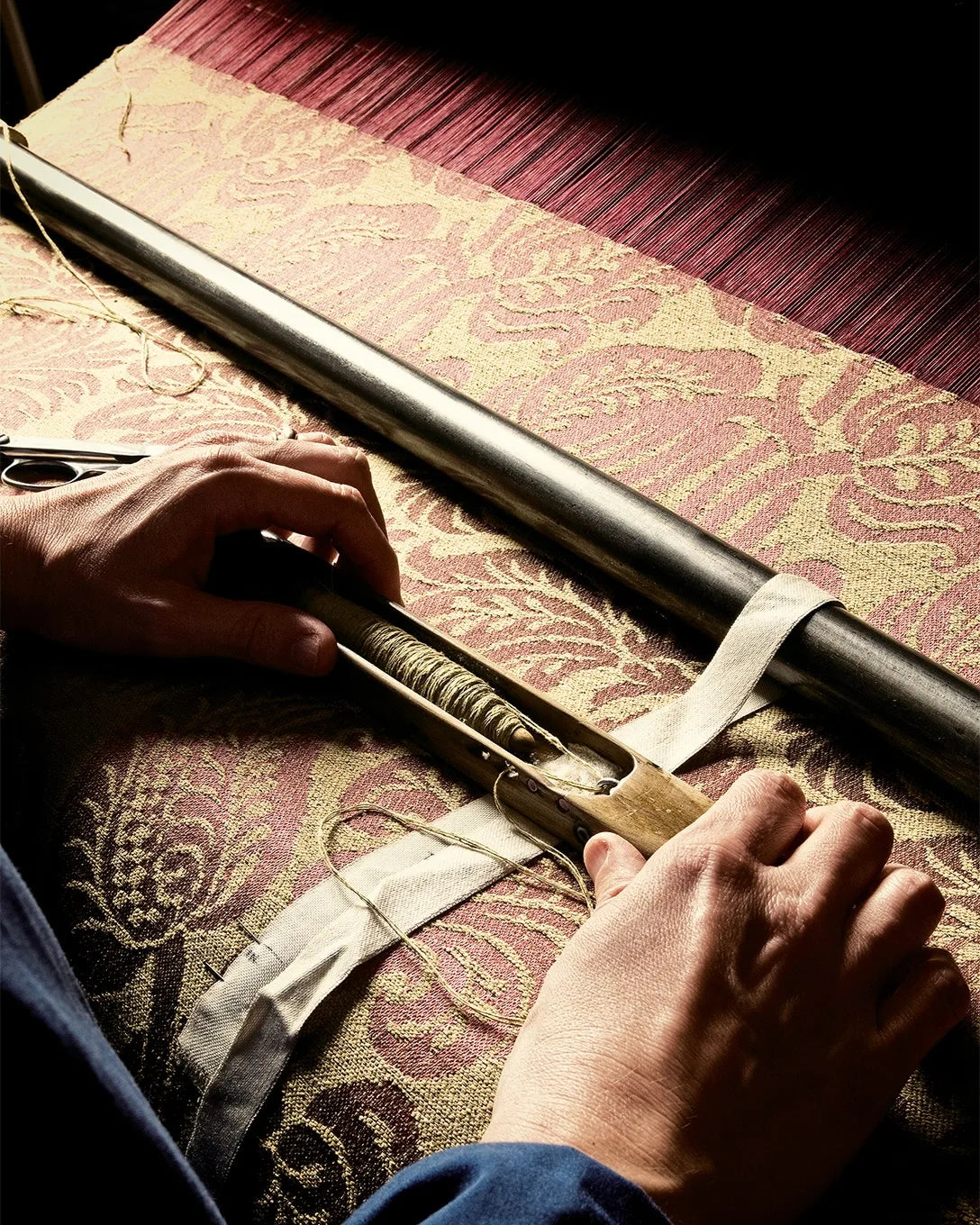 Artisan hand-weaving patterned silk on a wooden loom.