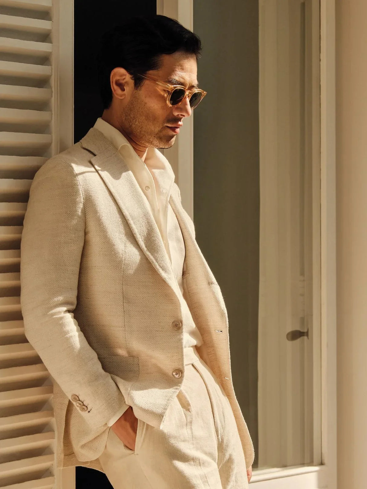 Man in cream sport coat and sunglasses by shutters