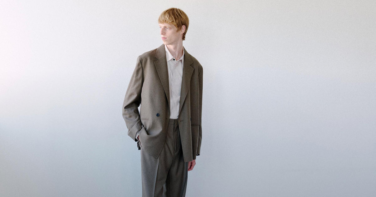 Man in Theory olive suit by a window
